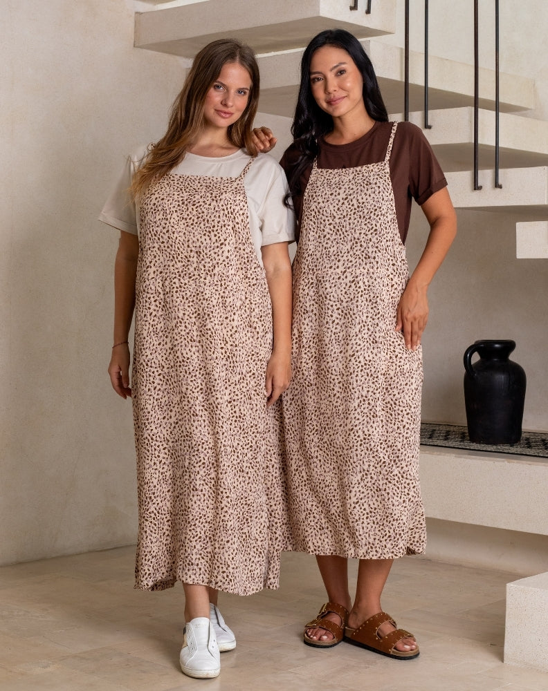 Woman standing in a modern kitchen wearing a white top and blue pants.