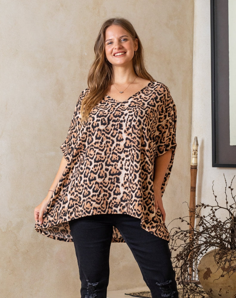 Woman wearing a leopard print top and black pants indoors.