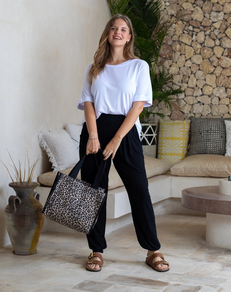 Woman holding a leopard print bag in a living room setting