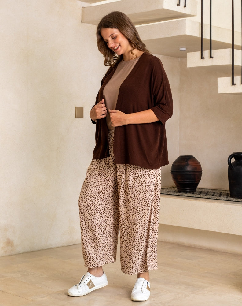 Woman wearing a brown top and leopard print pants indoors.