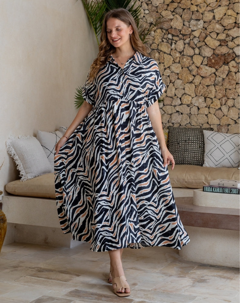 Woman in a zebra print dress standing in a living room.