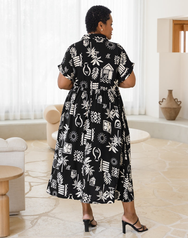 Woman wearing a black and white patterned dress in a room with light-colored flooring and furniture.