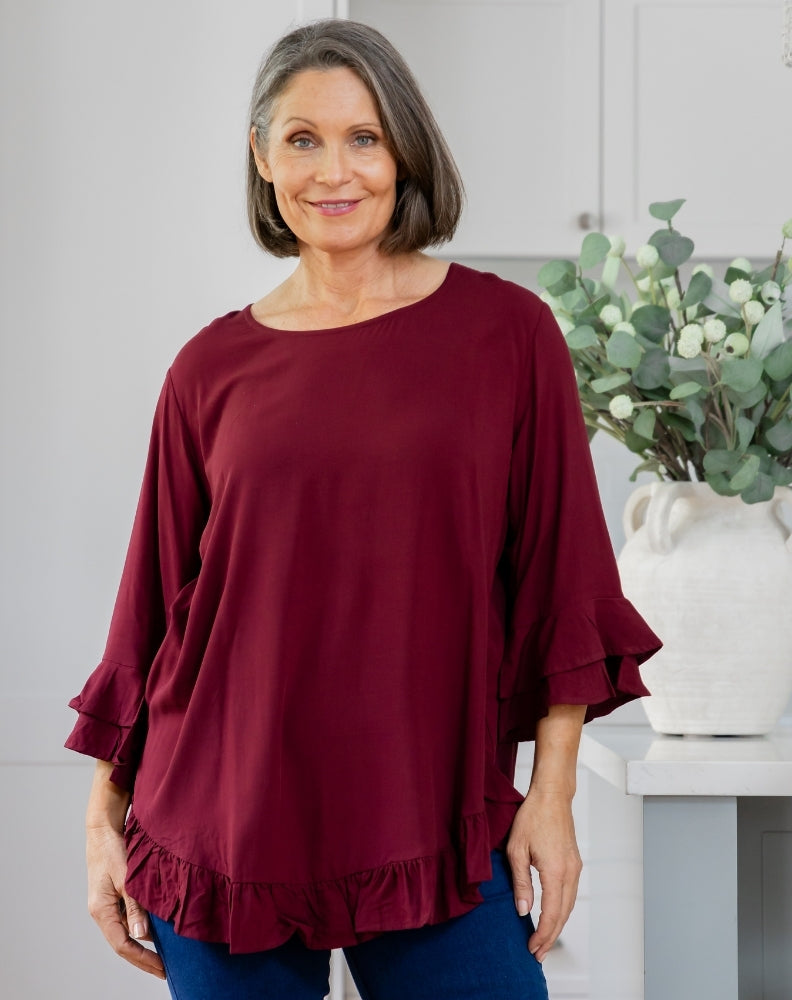 Woman wearing a burgundy ruffled blouse in a home setting