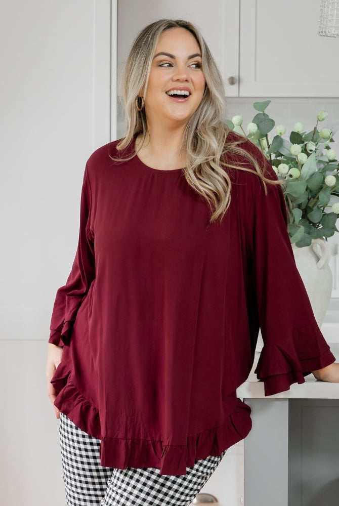 Woman wearing a burgundy top and checkered pants in a kitchen setting