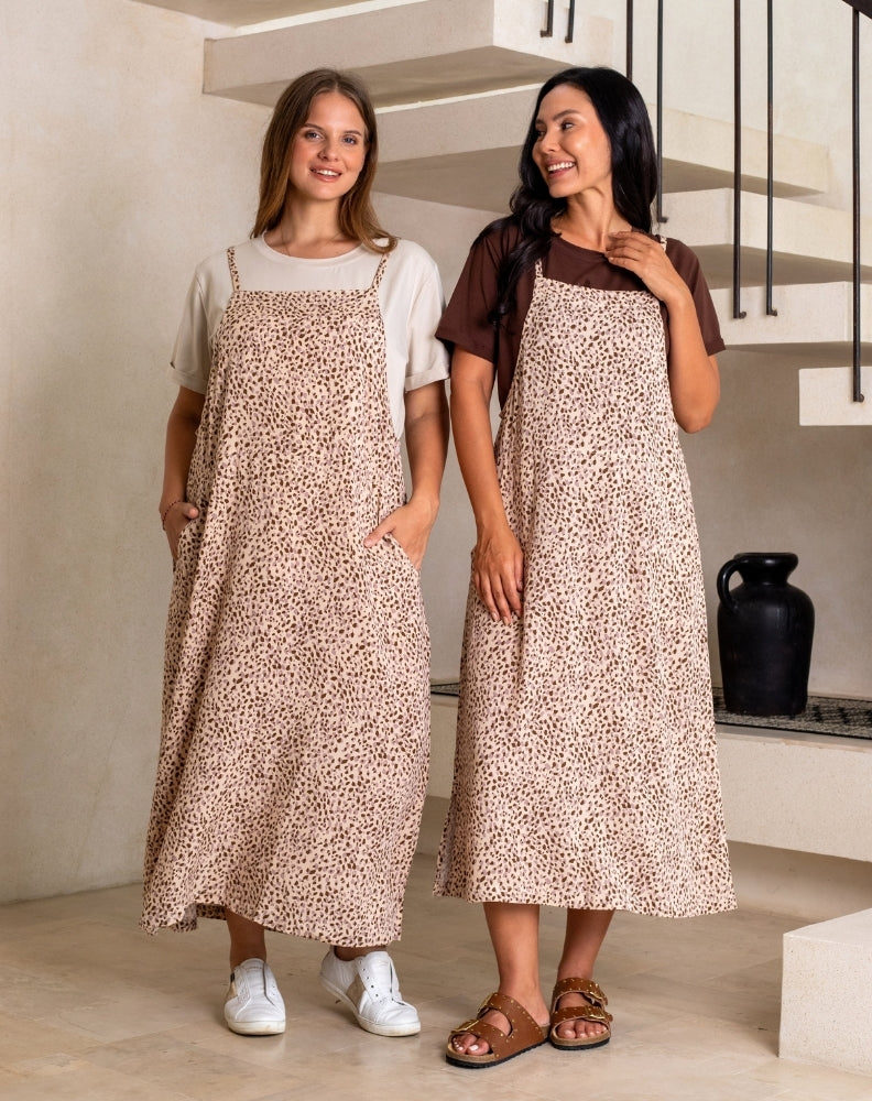 Two women wearing matching patterned aprons indoors.