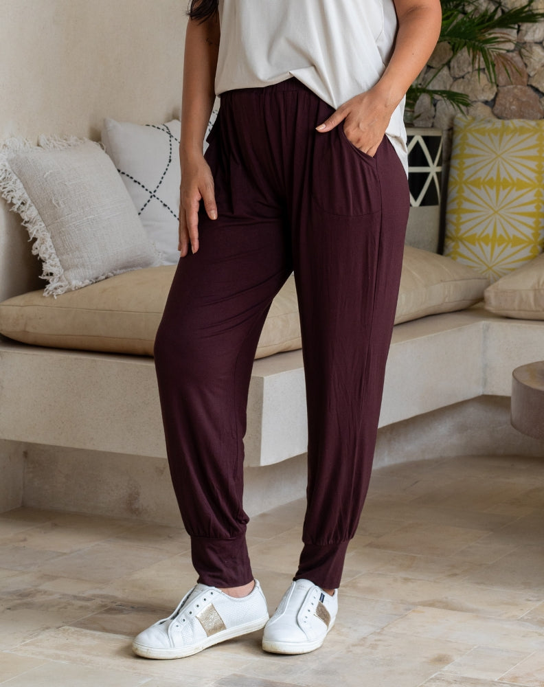 Person wearing maroon pants and white sneakers in a living room setting