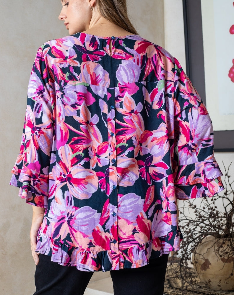 Woman wearing a colorful floral kimono-style top with a neutral background