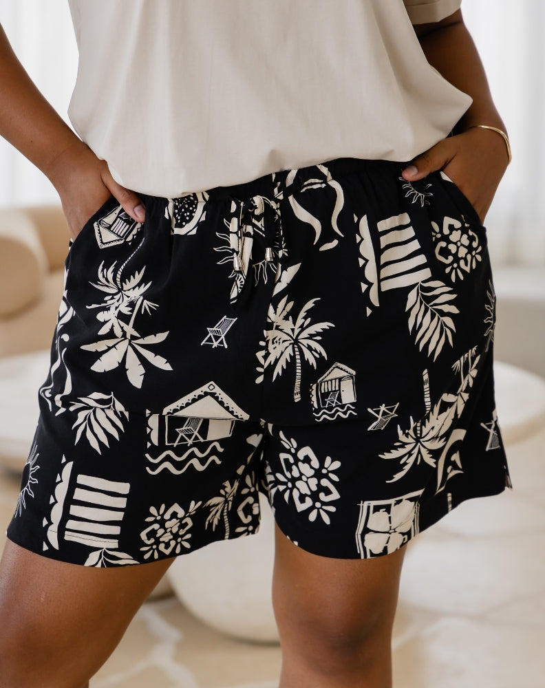 Black shorts with white patterns worn by a person indoors