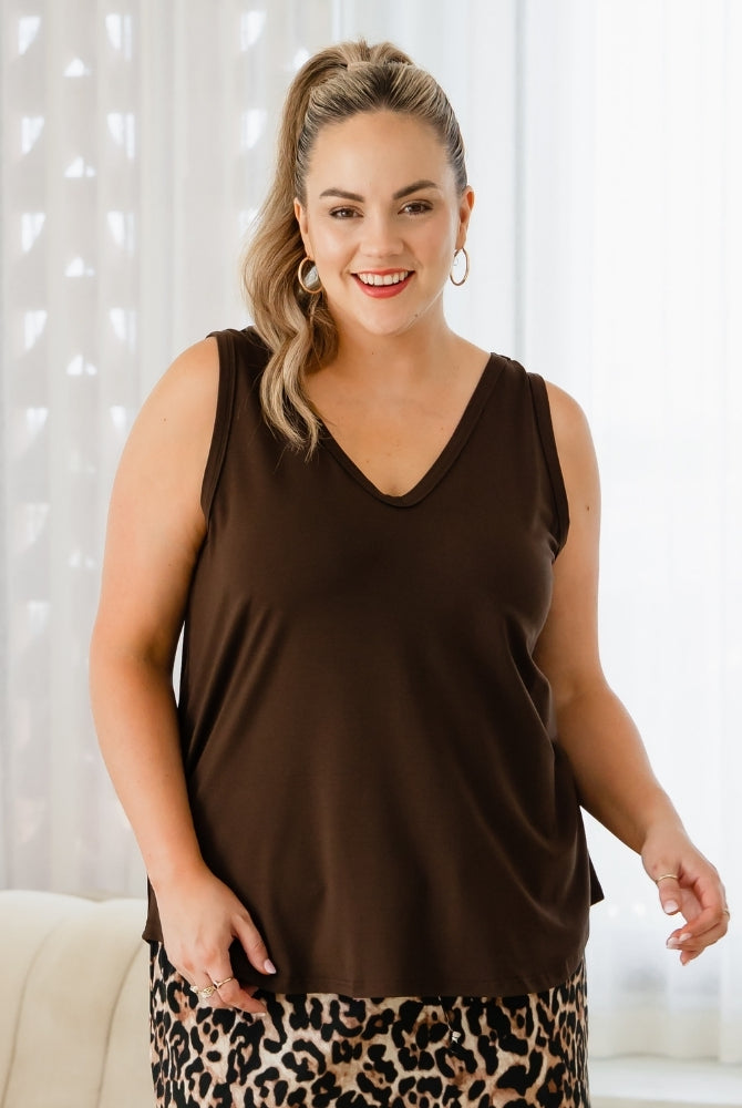 Woman wearing a brown sleeveless top with a leopard print skirt against a white curtain background