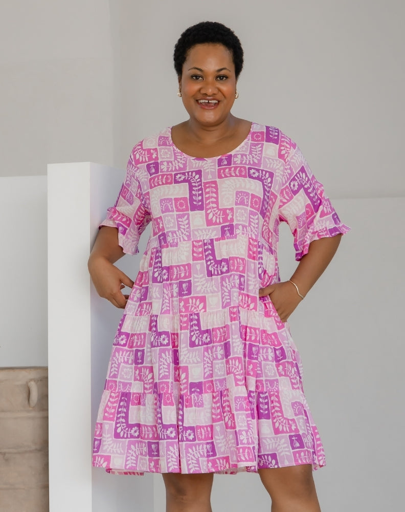 Woman wearing a pink and white patterned dress against a plain background