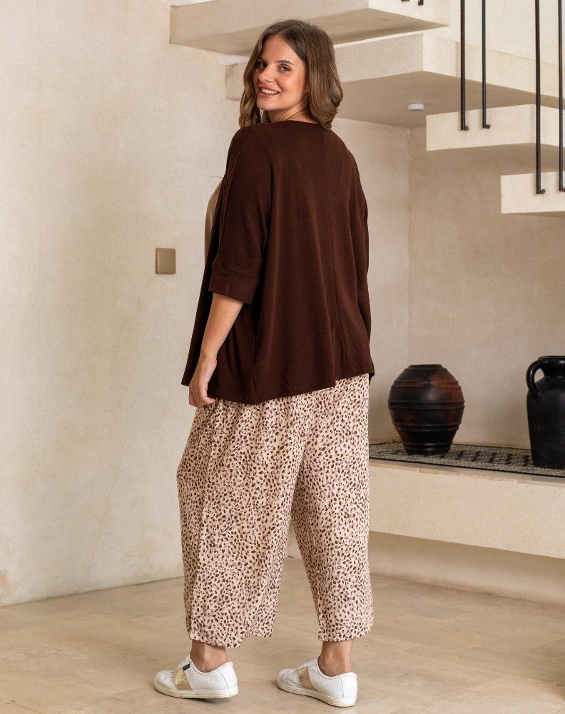 Woman wearing a brown top and leopard print pants in an indoor setting