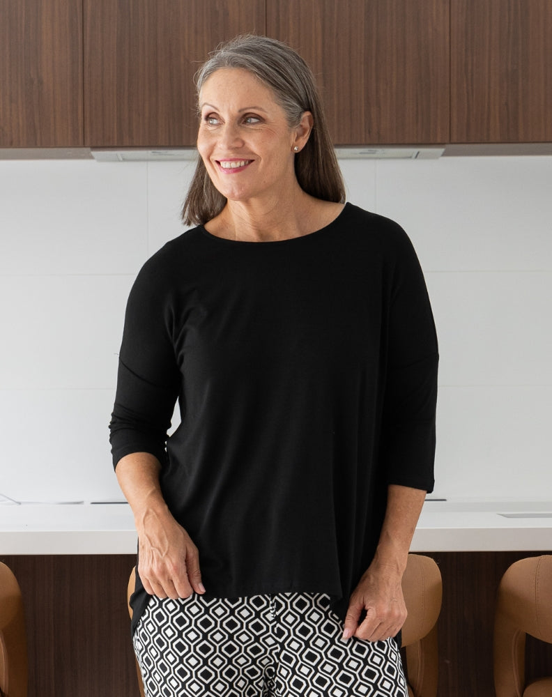 Woman wearing a black top and patterned pants in an office setting