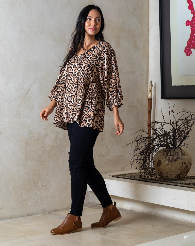 Woman wearing a leopard print top and black pants in an indoor setting.