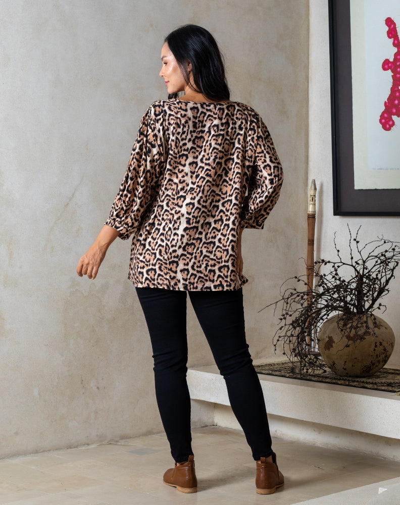 Woman wearing a leopard print top and black pants in an indoor setting.