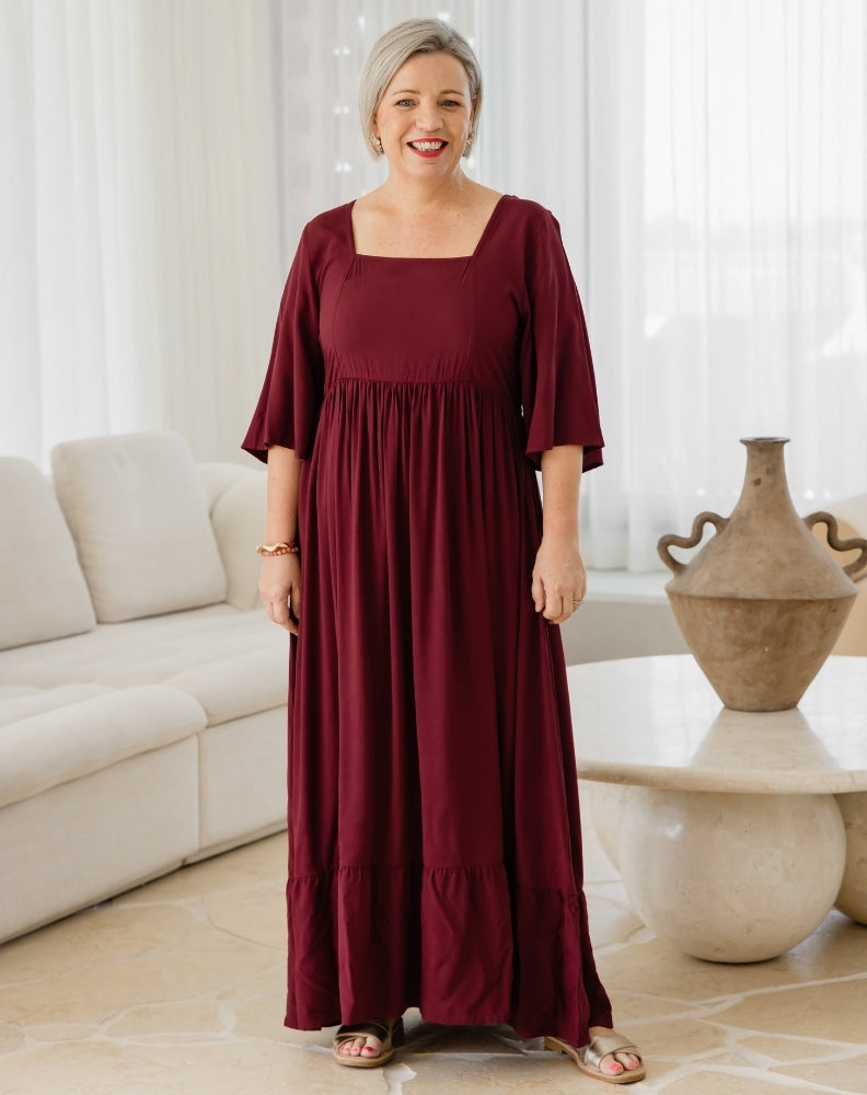 Woman wearing a burgundy dress in a living room setting