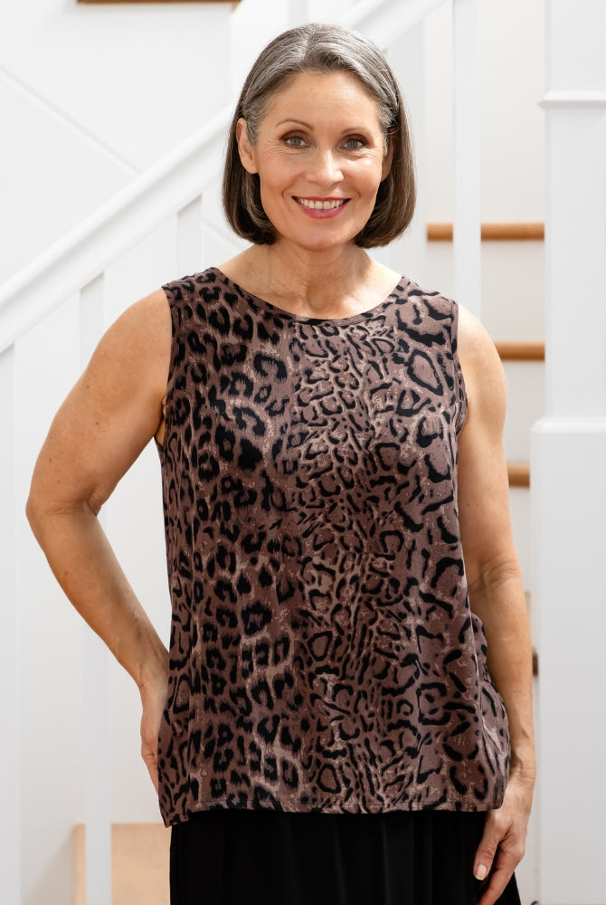 Woman wearing a leopard print sleeveless top standing in front of a staircase.