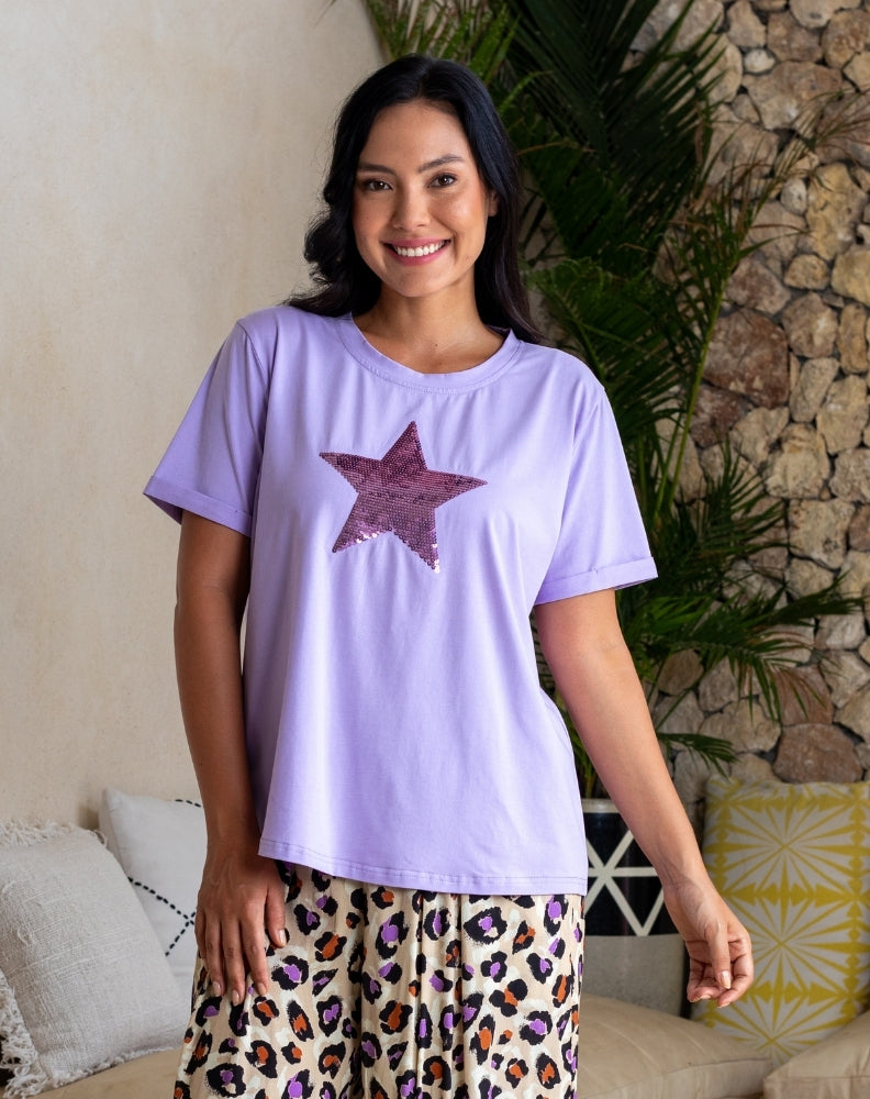 Woman wearing a purple t-shirt with a star design and leopard print pants in a casual setting.