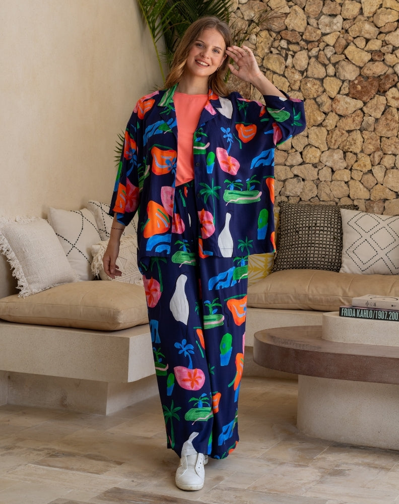 Woman in a colorful outfit standing in a living room with a stone wall background