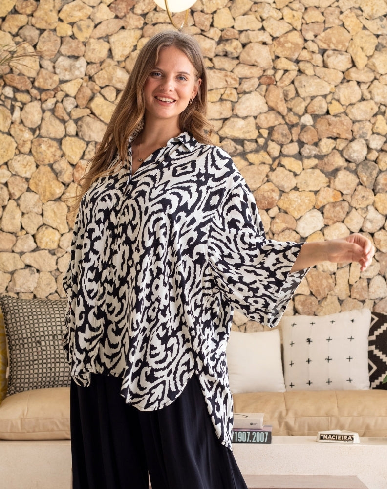 Woman wearing a black and white patterned blouse in a living room setting.