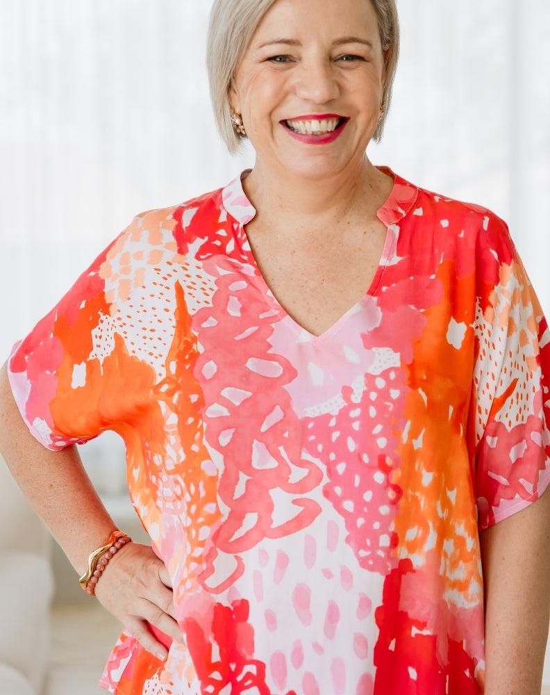 Woman wearing a colorful patterned blouse with a blurred background