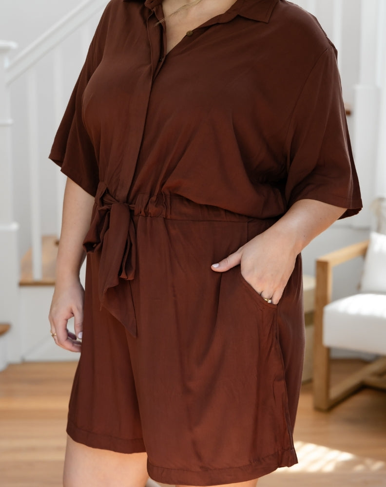 Person wearing a brown romper in an indoor setting