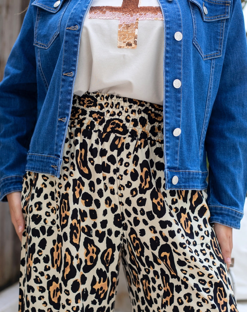 Person wearing a blue denim jacket, white shirt, and leopard print pants.