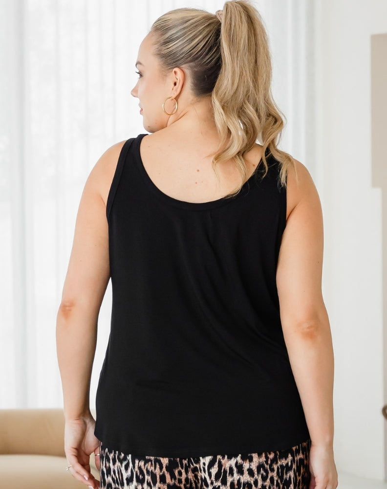 Woman wearing a black sleeveless top with a neutral background