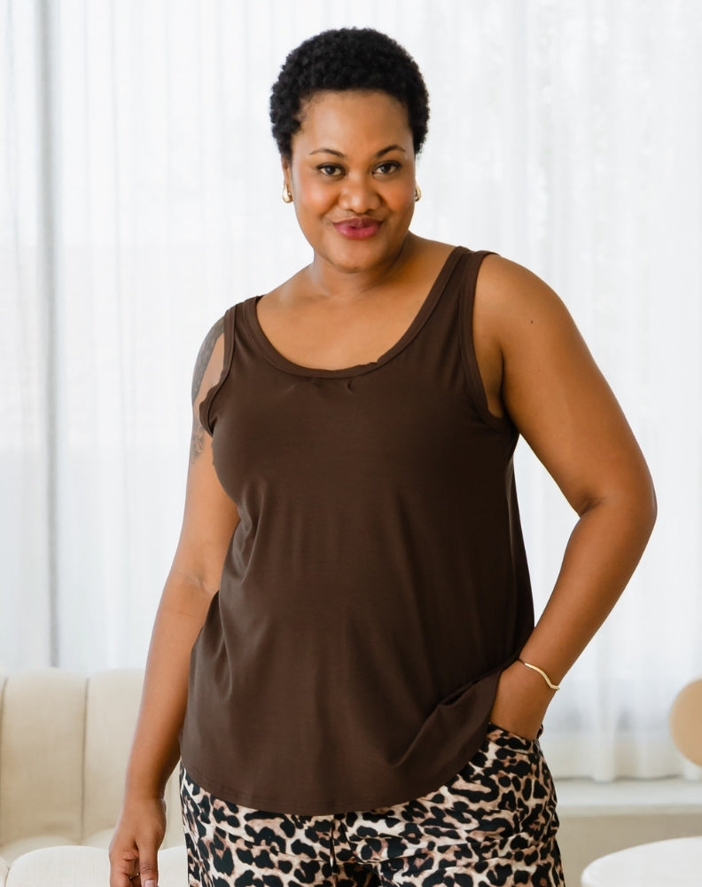 Woman wearing a brown sleeveless top and leopard print pants indoors.