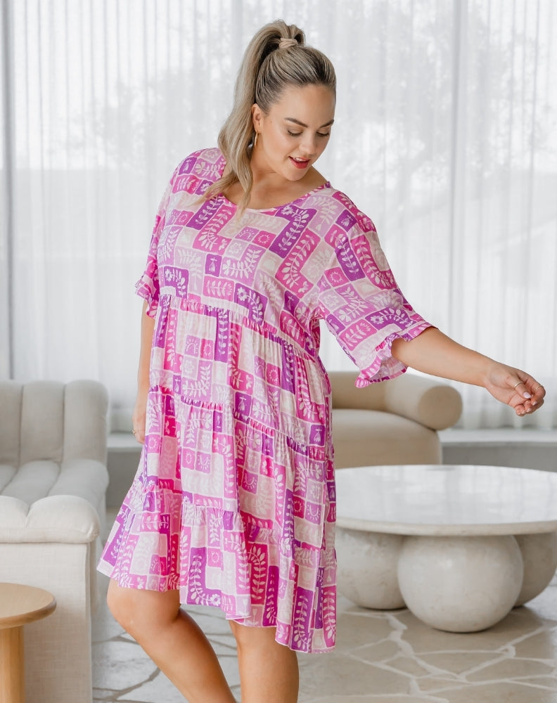 Woman wearing a pink and white patterned dress in a living room setting