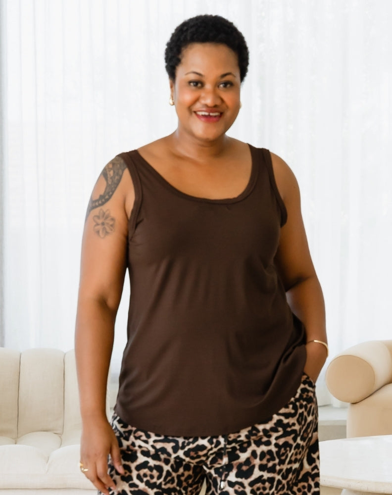 Woman wearing a brown tank top and leopard print pants in a living room setting.