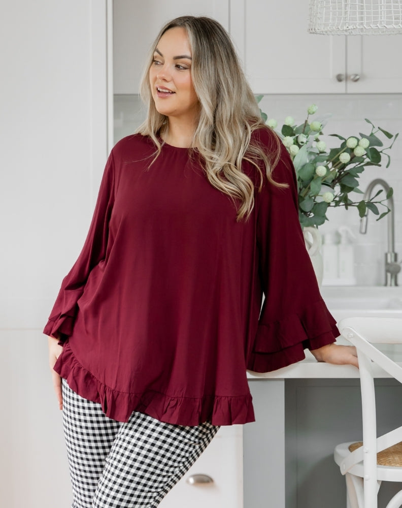 Woman wearing a burgundy top and checkered pants in a kitchen setting