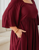 Person wearing a burgundy dress with a plain background