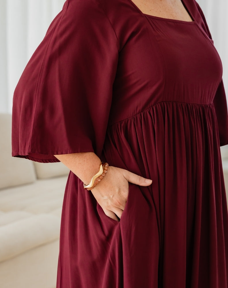 Person wearing a burgundy dress with a plain background