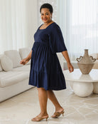 Woman wearing a navy blue dress in a living room setting