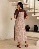Woman wearing a leopard print apron over a brown shirt in a room with vases on a shelf.