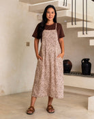 Woman wearing a leopard print dress over a brown shirt in an indoor setting.