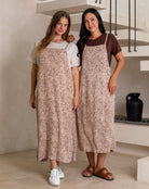 Woman standing in a modern kitchen wearing a white top and blue pants.