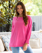 Woman wearing a pink sweater sitting on a couch outdoors.