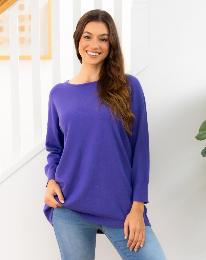 Woman wearing a purple tunic knit and blue jeans