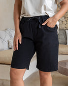 Person wearing black shorts and a white top in a casual indoor setting