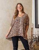 Woman wearing a leopard print top and black pants indoors.
