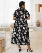 Woman wearing a black and white patterned dress in a room with light-colored flooring and furniture.