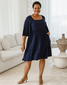 Woman wearing a navy blue dress in a living room setting