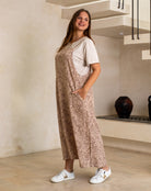 Woman wearing a leopard print dress and white sneakers in a modern interior setting.