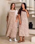 Two women wearing matching patterned aprons indoors.