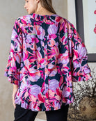 Woman wearing a colorful floral kimono-style top with a neutral background