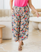 Person wearing colorful floral pants and a pink top in a living room setting.