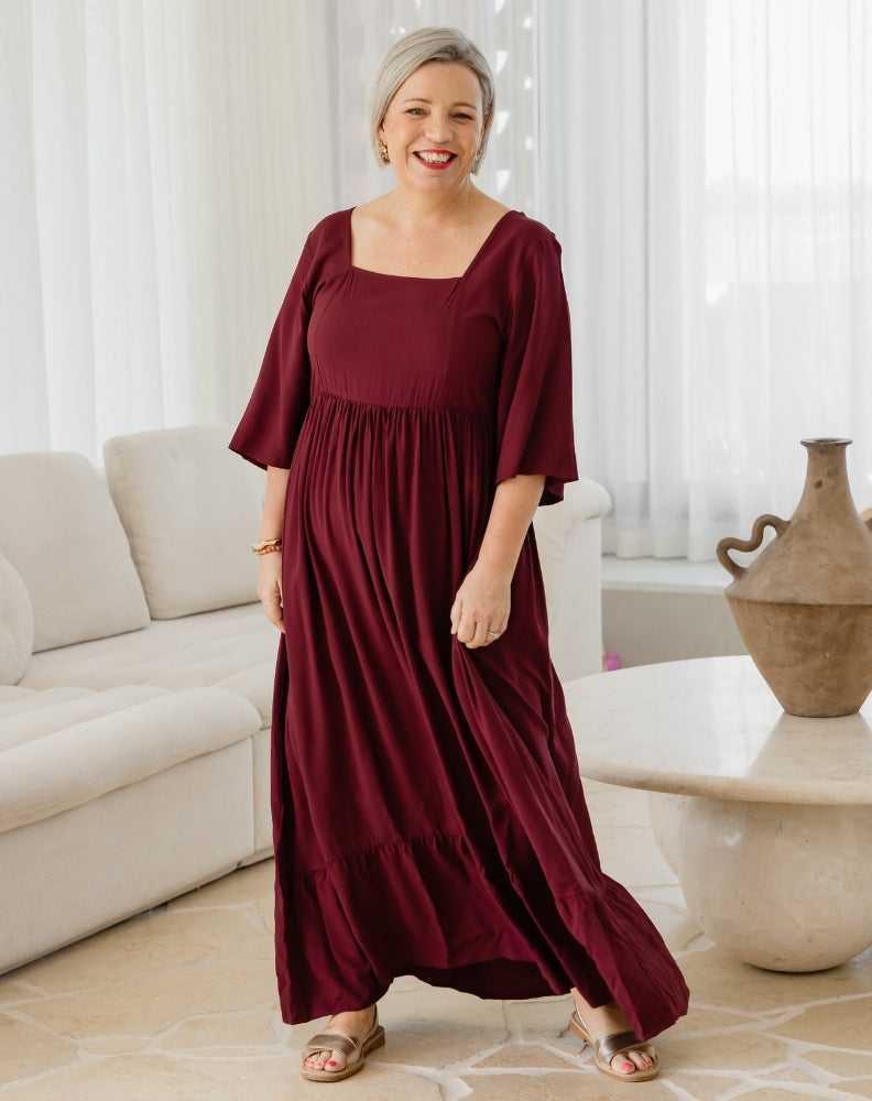 Woman wearing a burgundy dress in a living room setting