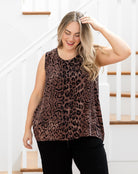 Woman wearing a leopard print sleeveless top and black pants in a home setting.