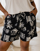 Black shorts with white patterns worn by a person indoors